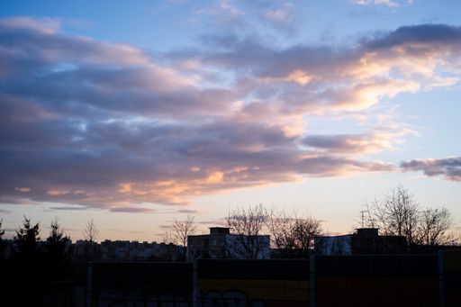 The silhouettes of buildings and trees under a cloudy sky during the sunset in the evening