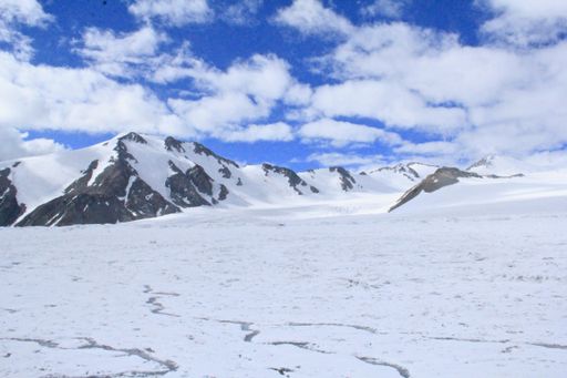 A landscape of rocks covered in the snow under the sunlight and a cloudy sky