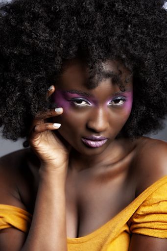 Beautiful African Woman with big curly  Afro and flowers in her hair. the black female model is wearing the pink make-up happily