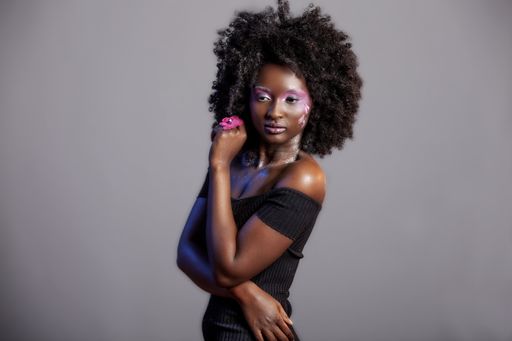Beautiful African Woman with big curly  Afro and flowers in her hair. the black female model is wearing the pink make-up happily