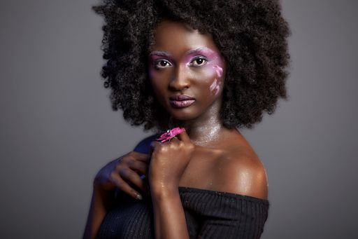 Beautiful African Woman with big curly  Afro and flowers in her hair. the black female model is wearing the pink make-up happily