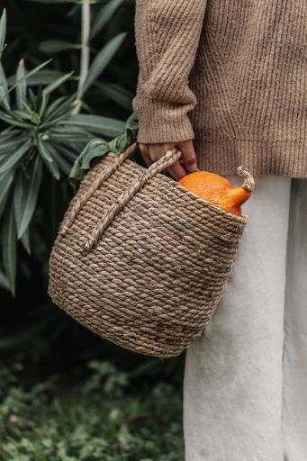 A closeup shot of a female hand holding a basket of pumpkins