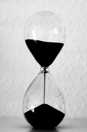 A vertical shot of black sand in an hourglass