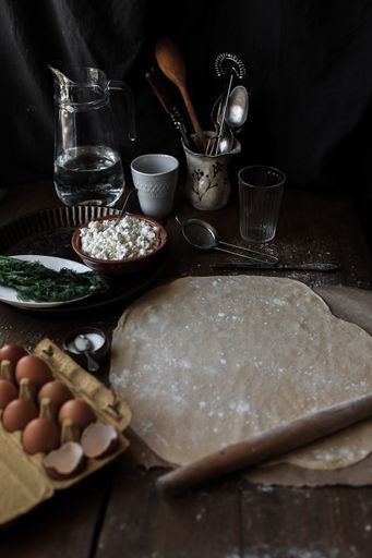 A vertical shot of a kitchen table with dough and ingredients for baking