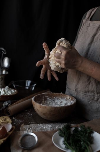 A vertical shot of female hands making dough in a wooden bowl