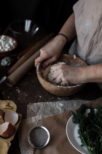 A vertical shot of female hands mixing dough in a wooden bowl