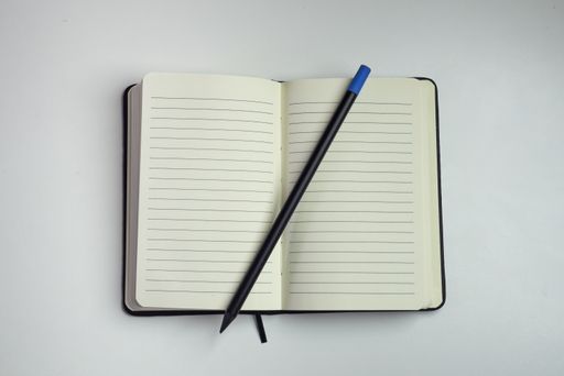 Opened notebook with empty white sheets with horizontal lines and a pencil with a white background