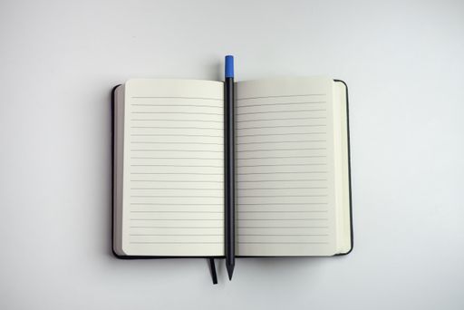 Opened notebook with empty white sheets with horizontal lines and a pencil with a white background