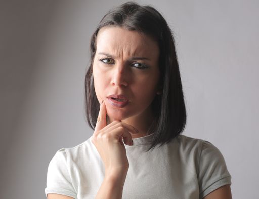 A closeup of a thoughtful Hungarian brunette looking at the camera with a confused, curious expression