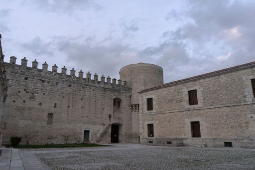 Historic stone castle with courtyard and cloudy sky in the background. Castle of Cuellar.