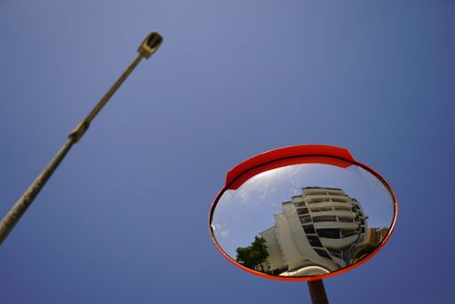 A low angle shot of a street mirror showing the building in front of it