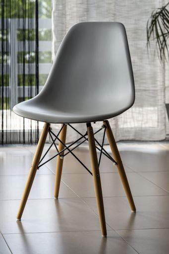 A vertical closeup of a modern white chair near the windows - interior concept