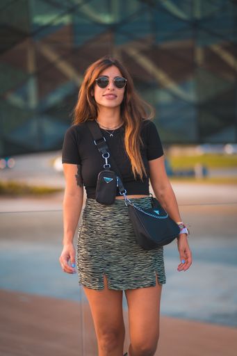 A street style of a young caucasian female in sunglasses walking in a street