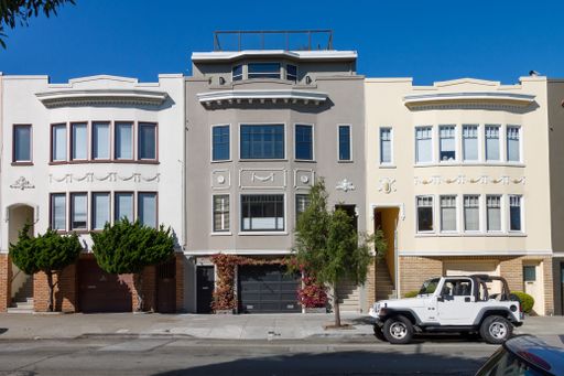 Row of historical residential houses on a sunny day with a parked white jeep in front. San Francisco, California