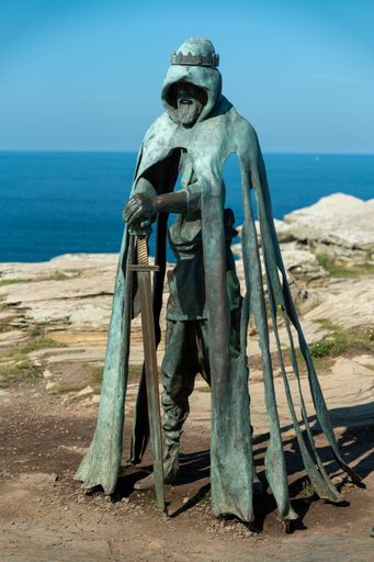Statue of King Arthur at Tintagel Castle with the ocean in the background on a clear day