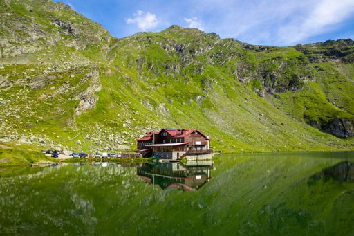 A tranquil mountain landscape with a lakeside cabin at Balea Lake in the Fagaras Mountains of Romania