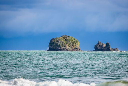 A scenic view of rocks in the ocean under a cloudy sky. Manuel Antonio National Park, Costa Rica