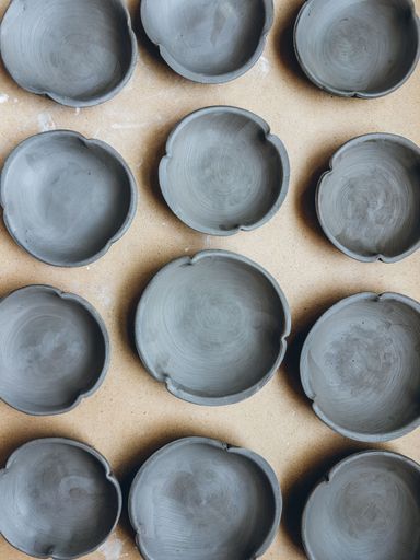 Handmade clay bowls arranged on a table, drying for a bisque fire