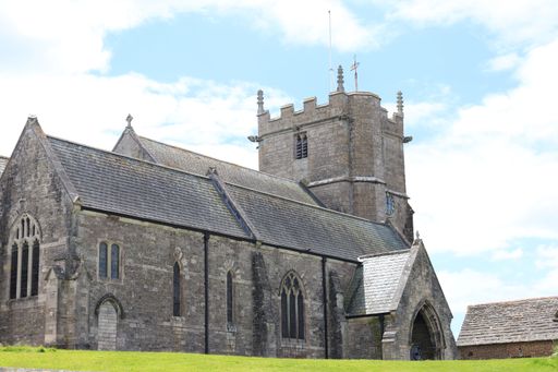 A historic stone church with a tower and arched windows under a partly cloudy sky in Corfe Castle