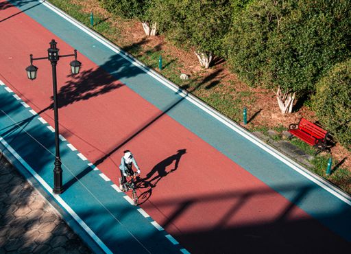 An aerial view of a cyclist riding on a bike path in Wuhan Park and the sunlight casts his figure onto the path in China