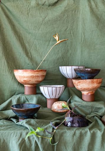 Artistic arrangement of ceramic flower holders with dried flowers on a green fabric background