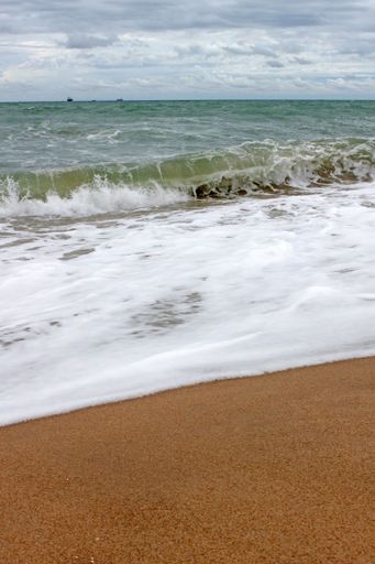 The foamy waves washing the sand beach on a sunny day