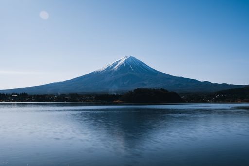 A beautiful landscape of Mount Fuji with a clear blue sky and calm lake in the foreground