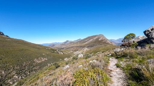 A scenic view of a grassy mountain landscape under a clear blue sky. South Africa