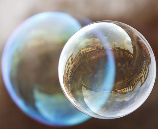 A closeup of residential buildings reflecting in a soap bubble under the sunlight