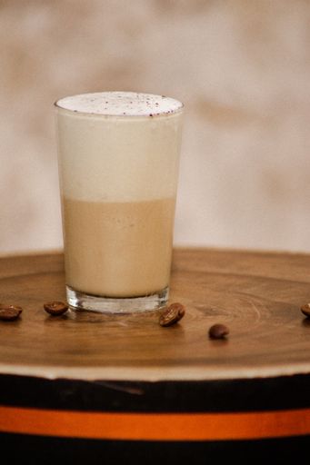 Coffee and milk cocktail with coffee beans next to it
