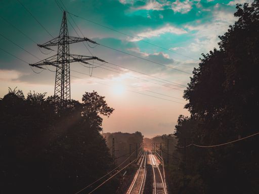 A stunning view of two parallel railroads through lush trees under a cloudy sky at dusk