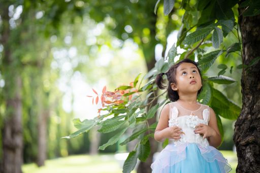 A cute Asian child with a blue dress playing in a park