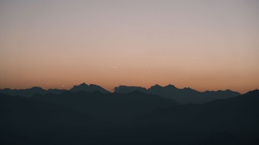 A silhouette of the mountain range at sunset with a clear sky and soft gradient colors.