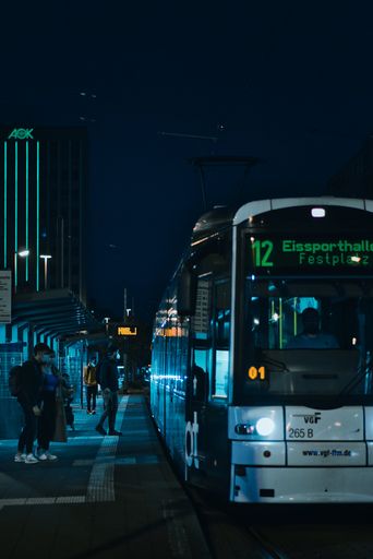 A vertical shot of people waiting for public transports at night in Frankfurt, Germany