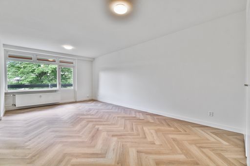 a large white room with laminate flooring and curtainless windows