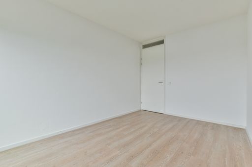 an empty white room with a close door and laminate flooring