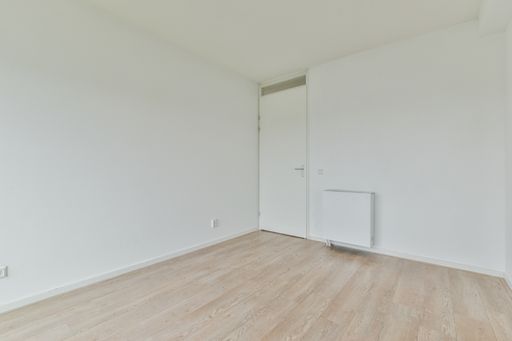an empty white room with a close door and laminate flooring