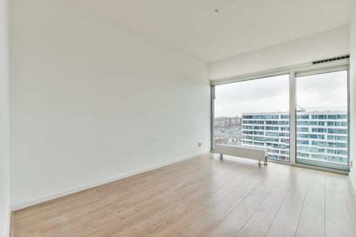 an empty white room with laminate flooring and french windows