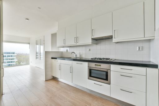 an empty white kitchen with laminate flooring and closets