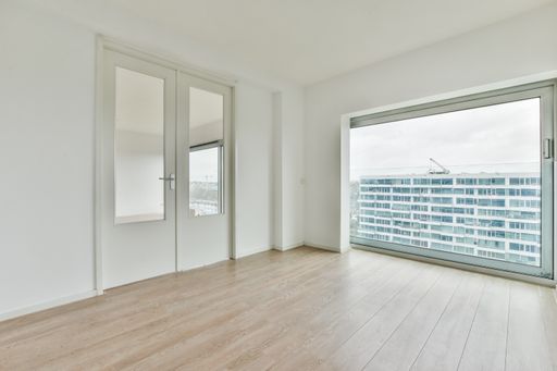 an empty white room with a door, large windows and laminate flooring