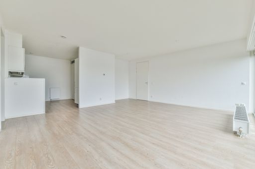 an empty white large room with laminate flooring
