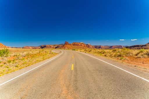 An empty road with majestic cliffs in the background. Canyonlands National Park, Utah