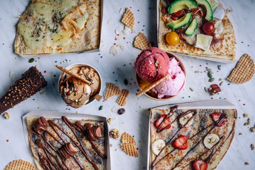 A top view of a variety of crepes and ice cream on a marble table