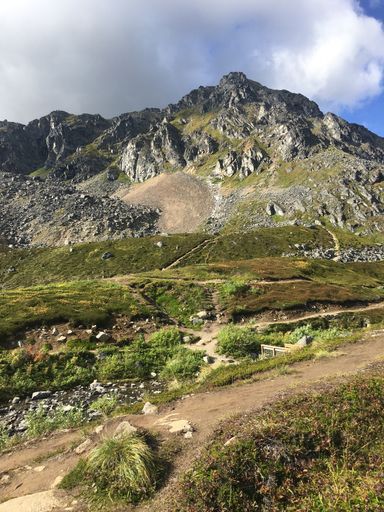 A vertical shot of a rocky mountain landscape with narrow paths under a cloudy sky