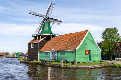 A scenic view of Zaanse Schans, a historic mill village with centuries-old windmills and timber houses by the river