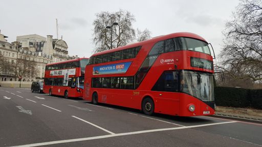 A red double-decker bus drives next to a motorcycle over the London bridge in London, England