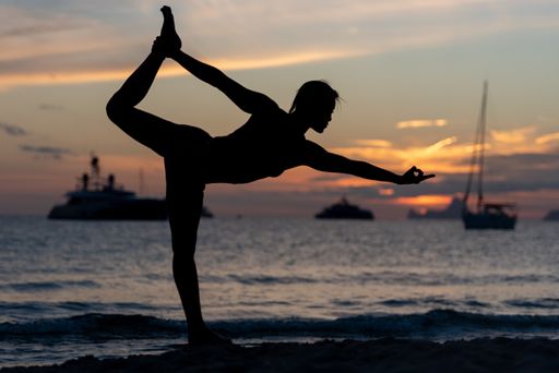 A Silhouette of Fitness model doing yoga at sunset time.