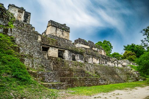 Ancient Mayan temple ruins in Tikal, Guatemala, with lush greenery and a clear blue sky.