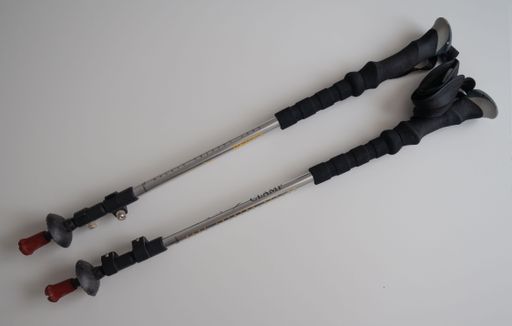 A pair of black and silver trekking poles with ergonomic grips and adjustable length, placed on a white background.
