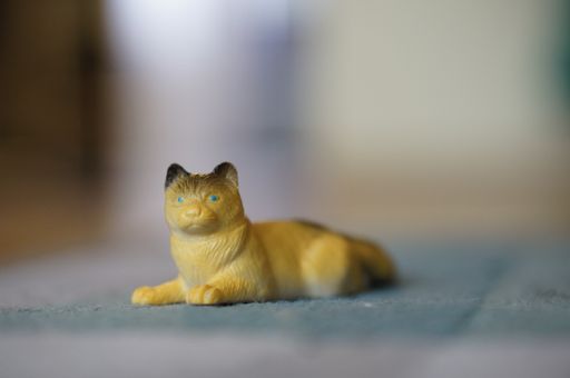 A closeup shot of a yellow plastic toy cat on a carpet